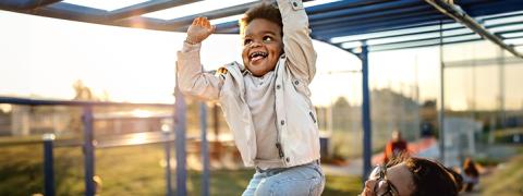 Un petit garçon joue joyeusement sur un portique d'escalade avec sa mère