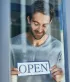 Jonge ondernemer toont een bordje met de tekst 'Open'