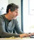 Man bekijkt zijn financiële toestand op zijn laptop aan de keukentafel
