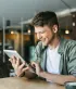 Een jonge ondernemer werkt tevreden op zijn tablet in de koffiehoek