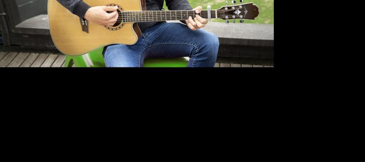 Een jonge kerel speelt op zijn gitaar