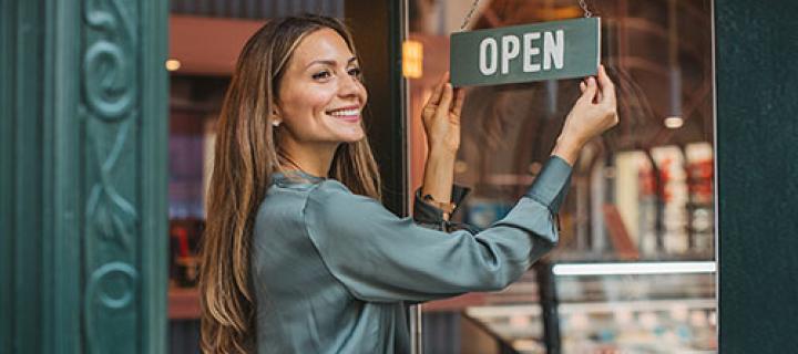 La vendeuse retourne le panneau « ouvert » sur la porte du magasin avec un sourire