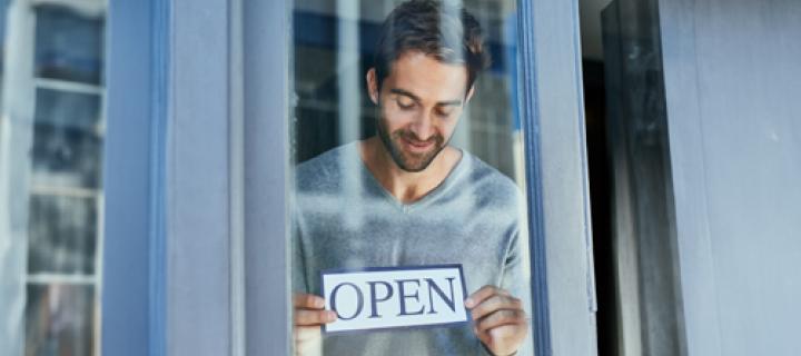 Jonge ondernemer toont een bordje met de tekst 'Open'