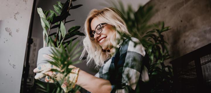 Blonde vrouw met bril genietend van haar kamerplantje