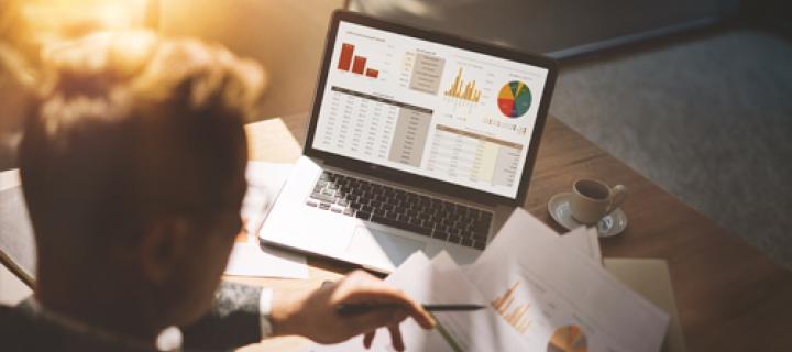 Man bekijkt de beursgrafieken op zijn laptop