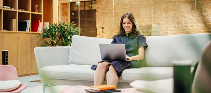 Jonge vrouw kijkt ontspannen op haar laptop in de zetel