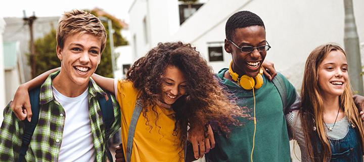 4 scholieren staan lachend arm in arm