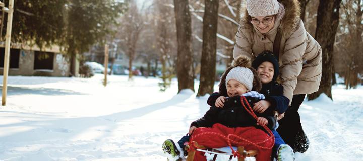 Vrouw speelt met haar 2 kindjes in de sneeuw