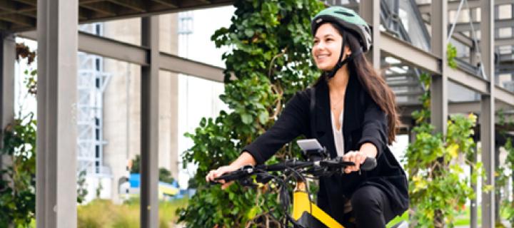 Jonge vrouw met fietshelm lachend op haar gele fiets
