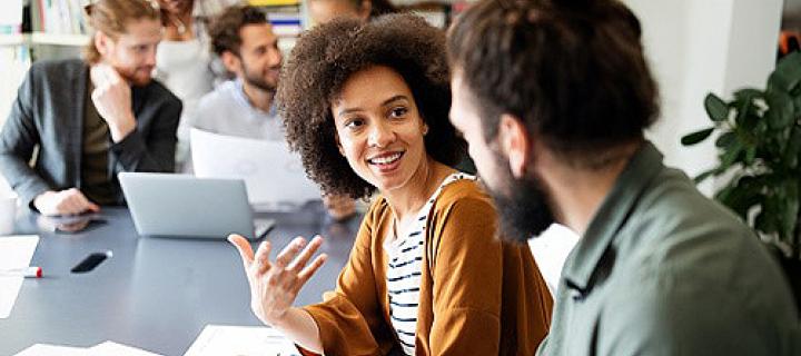 Jonge vrouw in gesprek met haar collega op kantoor