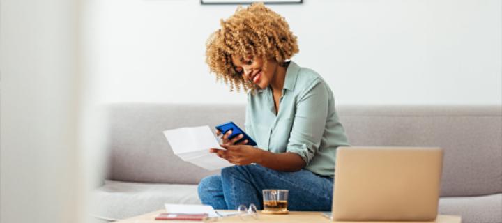 Jonge vrouw in haar zetel betaalt een factuur via smartphone