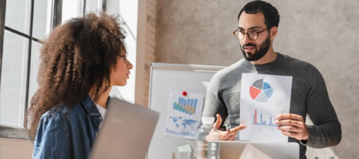 Un homme montre des graphiques à sa collègue au bureau
