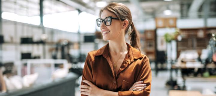 Jonge onderneemster met bril bekijkt lachend haar handelszaak