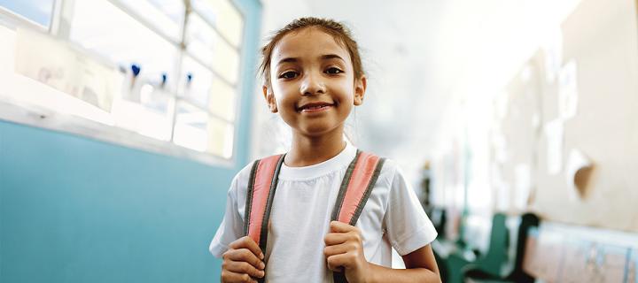 Une fille à l'école montre fièrement son cartable