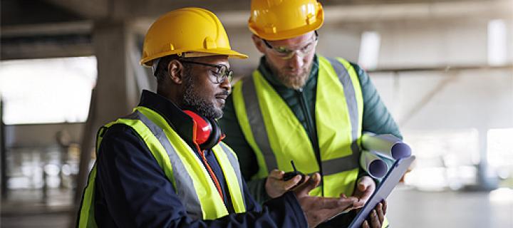 2 mannen met veiligheidshelm bekijken een bedrijfspand