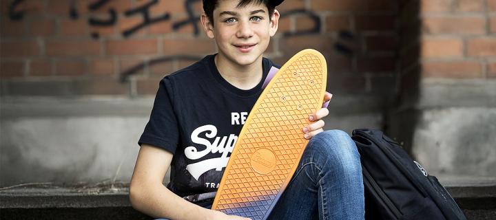 Een lachende jongen met pet en skateboard