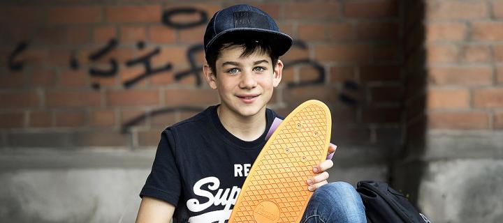 Een lachende jongen met pet en skateboard