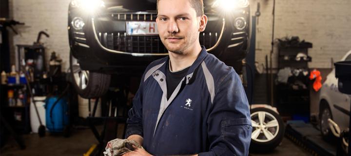 Een jonge garagist werkt aan het onderhoud van een wagen