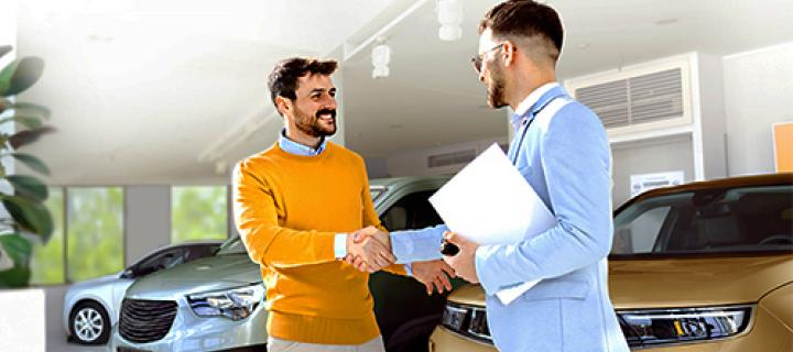 Een man schudt tevreden de hand van zijn autoverkoper