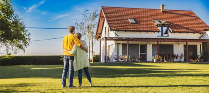 Een koppel bekijkt hun woning vanuit de grote tuin